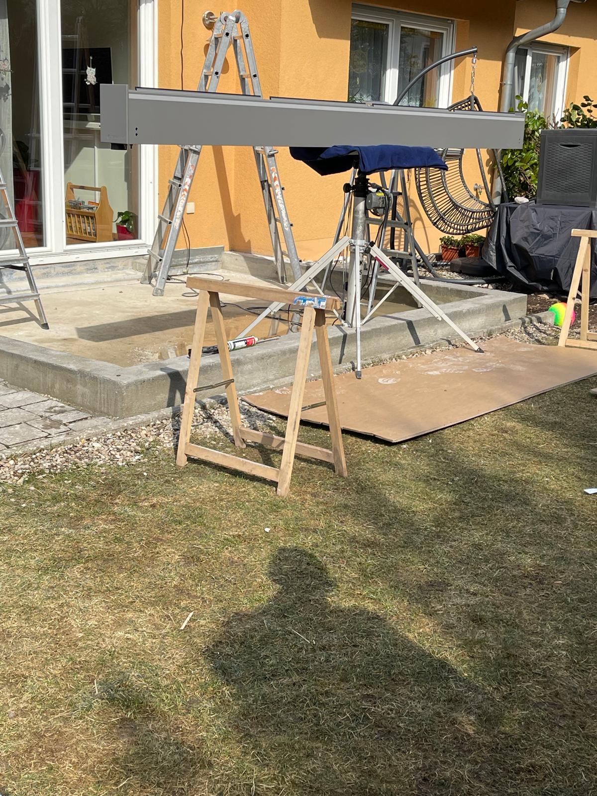 Montage einer großen Markise mit Stativ und Leiter im Garten
